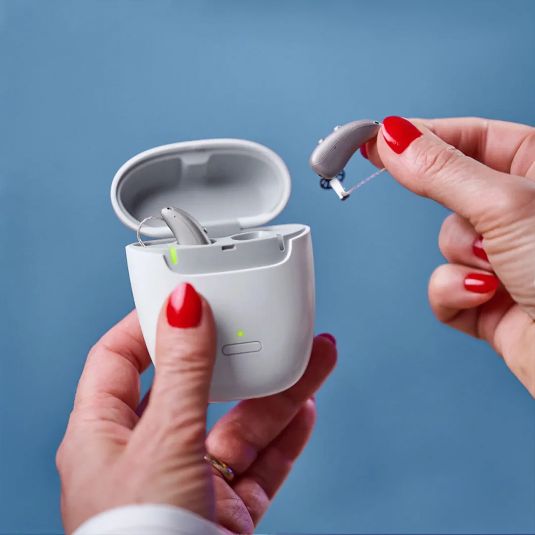 Person handling a rechargeable hearing aid and charging case